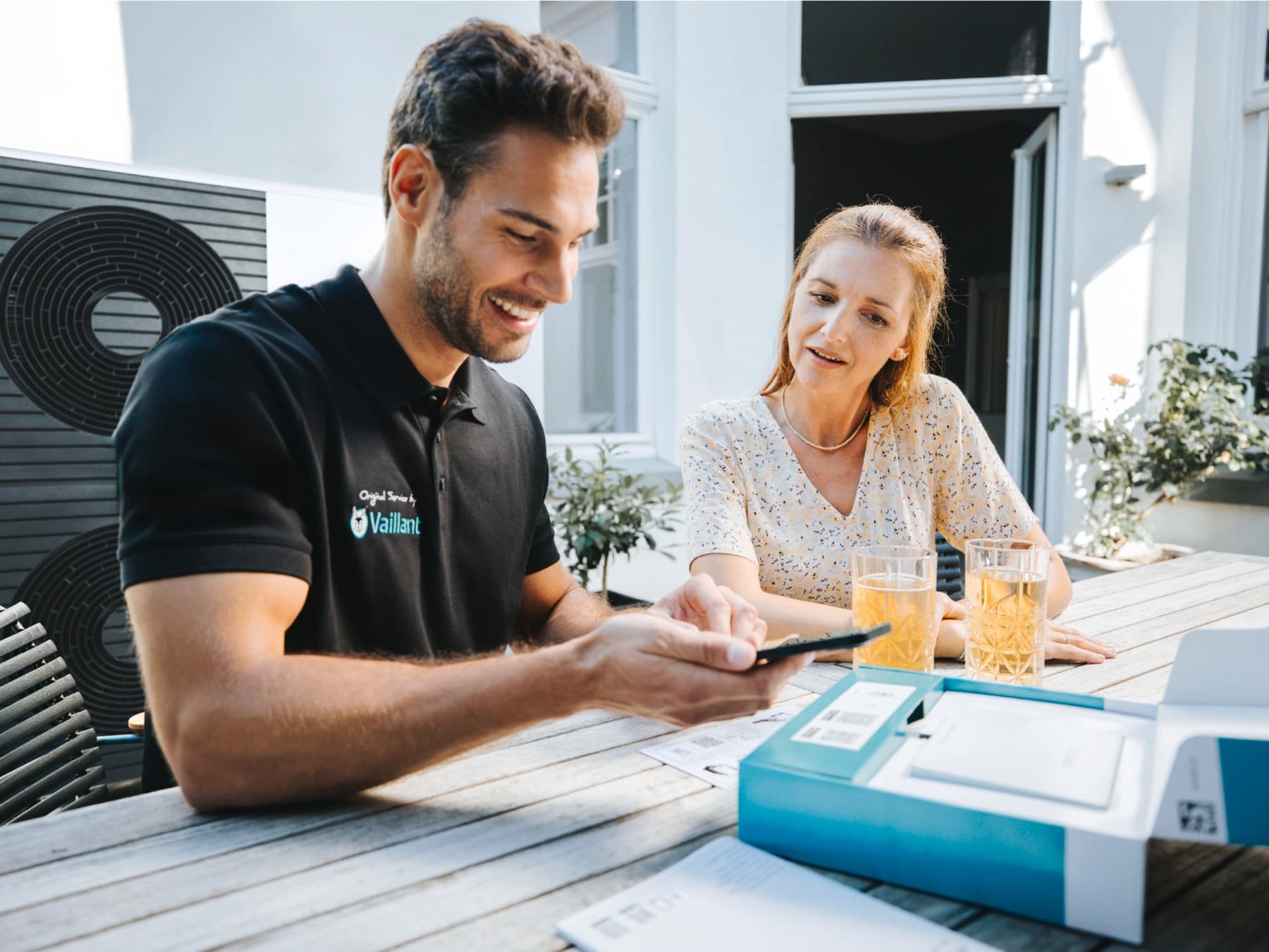 Vaillantov servisni tehnik s pametnim telefonom in stranko ob sebi